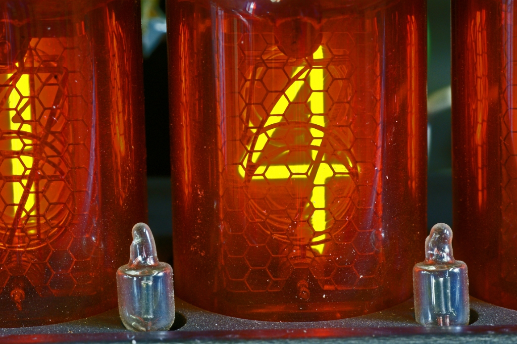 DSC04858.JPG - View into one of the Nixie tubes: the honeycomb grillage is the anode (at + 150 VDC). The digit-shaped cathodes also are clearly visible. The active cathode willbe surrounded by the neon glow discharge. The small transparent tubes at the front also are cold cathode neon tubes used to indicate the decimal point.