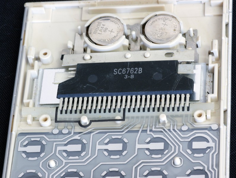 DSC07776.JPG - The white plastic cut-out seen in the previous pictures bends the chip pins against the connecting pads on the plastic keyboard backplane. The LCD display lies below the chip. 